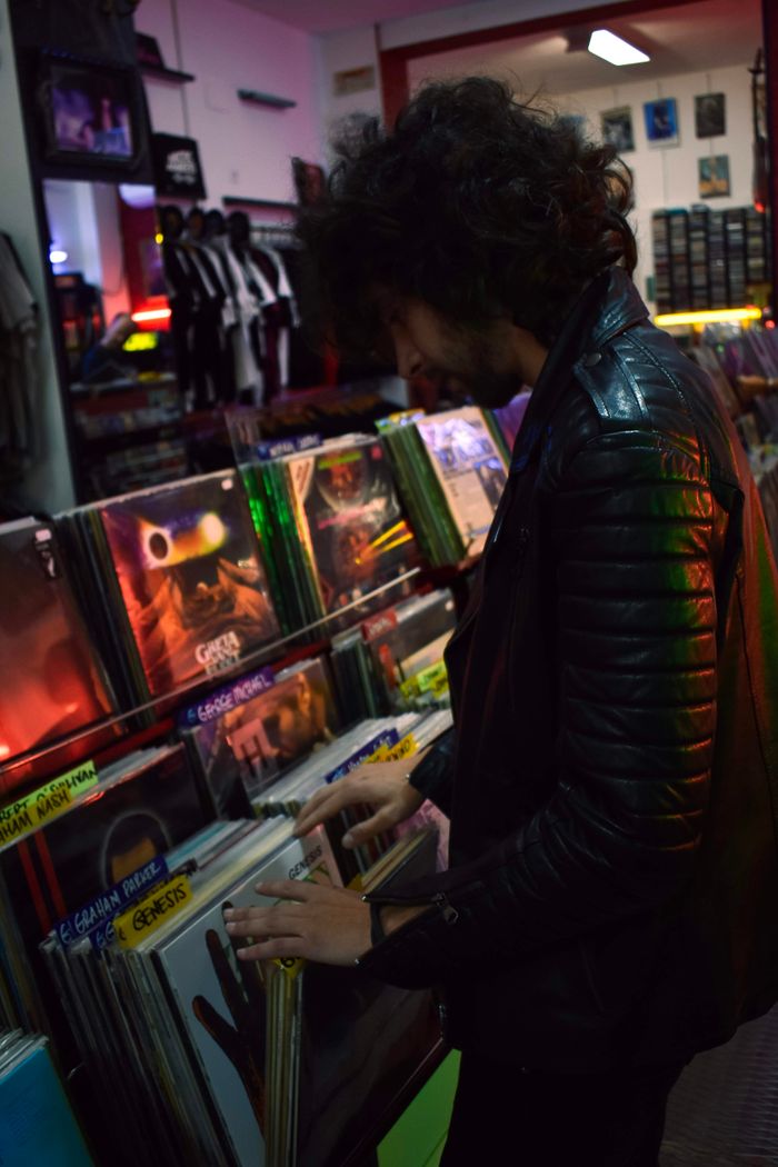A man in a black leather jacket browses vinyl records at a store in Sevilla, Spain.
