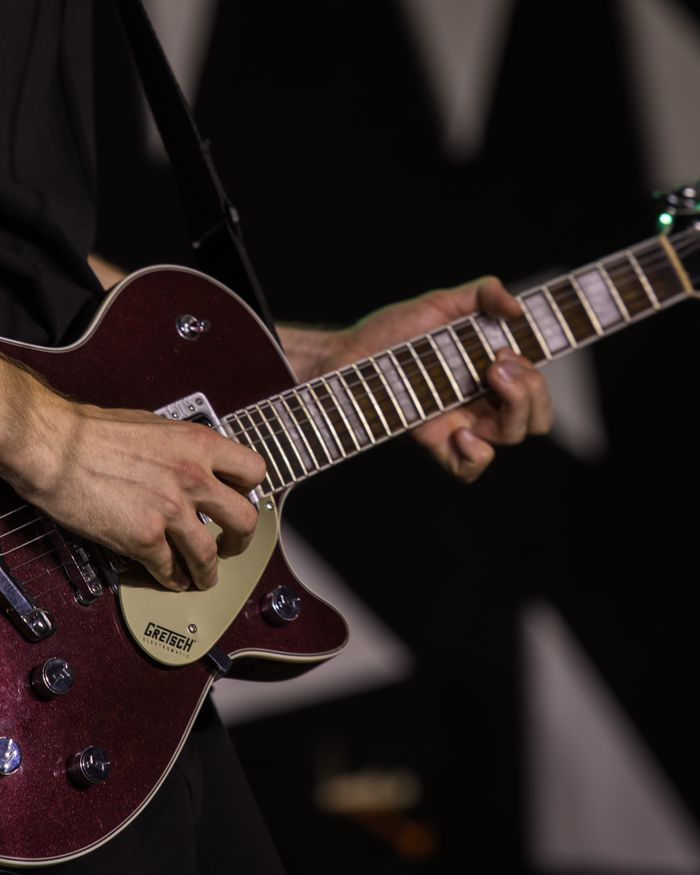Musician passionately plays a Gretsch electric guitar during a live performance.