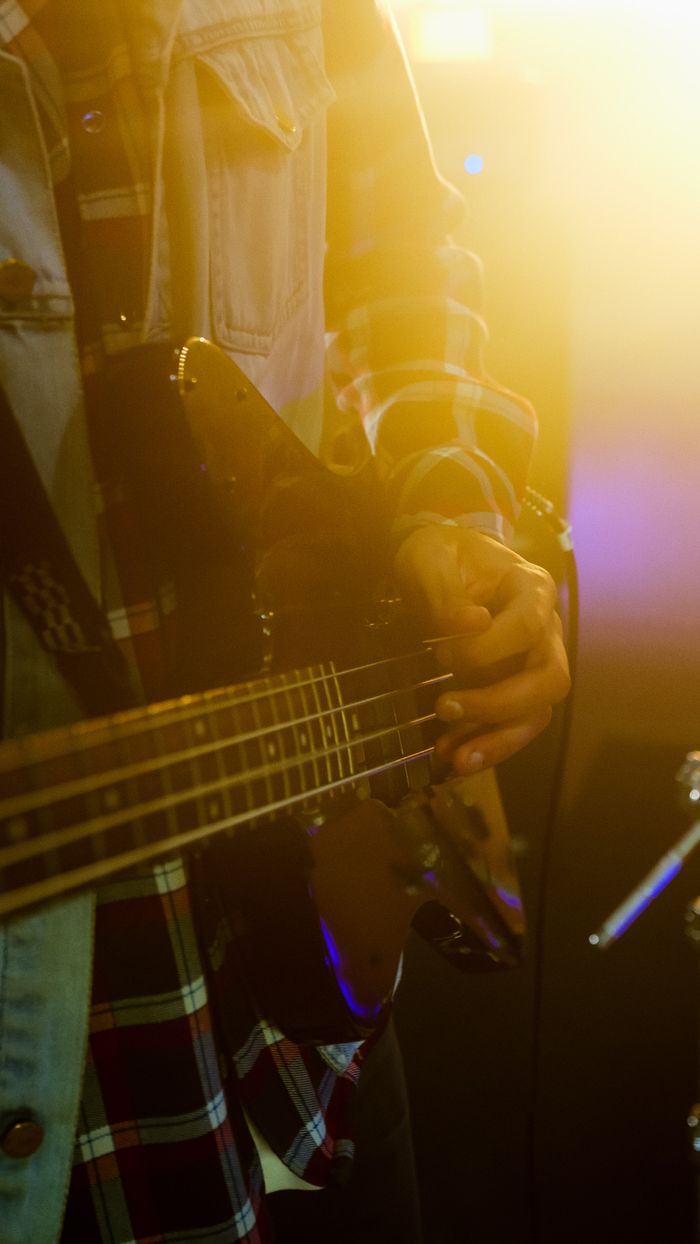 Close-up of a musician strumming an electric guitar with dramatic lighting.