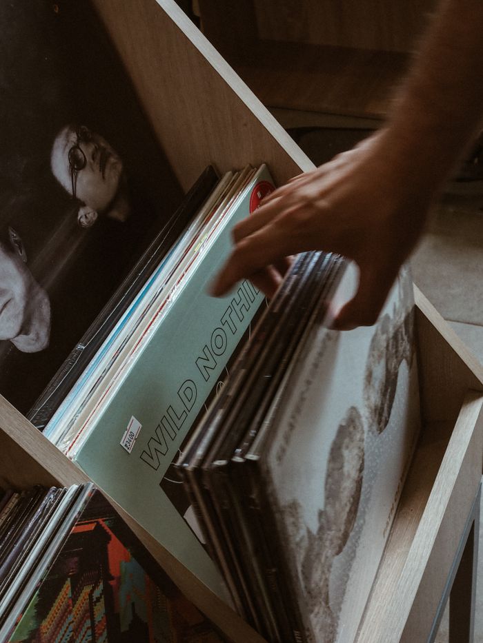 Close-up of a hand browsing vintage vinyl records in a store setting.